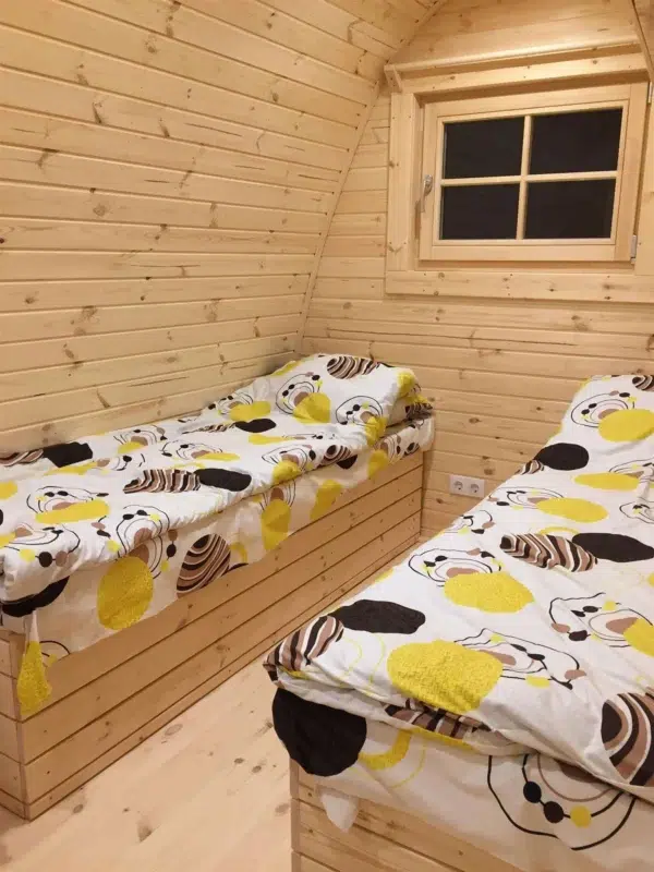 Wooden camping pod, interior twin beds beneath a window