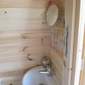 Wooden camping pod, interior washbasin and wall mirror