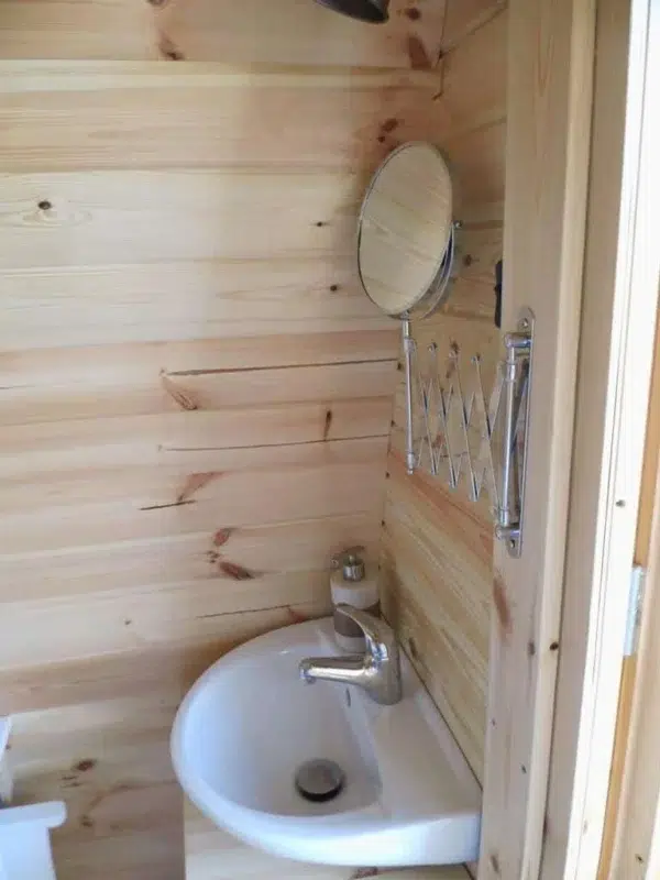 Wooden camping pod, interior washbasin and wall mirror