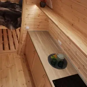 Wooden camping pod, kitchen counter beside sleeping area