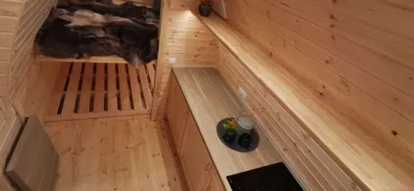 Wooden camping pod, kitchen counter beside sleeping area