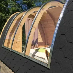 Wooden camping pod, large curved roof glazing viewed from outside