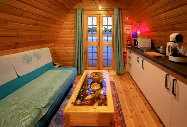 Wooden camping pod, living area with sofa, table and kitchenette
