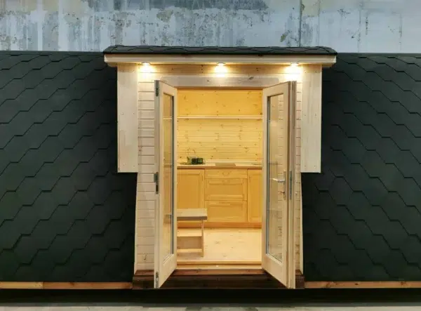 Wooden camping pod, open double doors revealing kitchenette