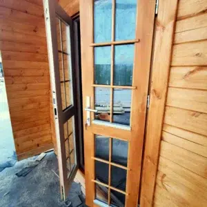Wooden camping pod, open glazed entrance doors viewed from inside