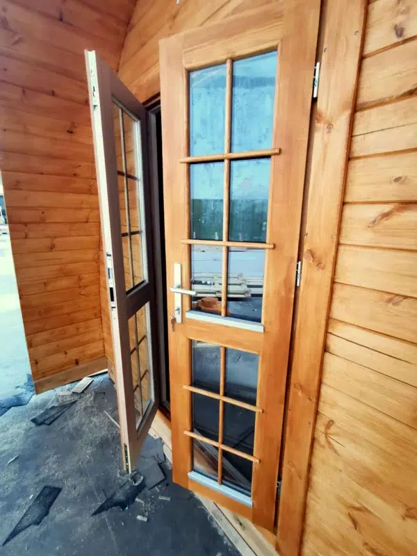 Wooden camping pod, open glazed entrance doors viewed from inside