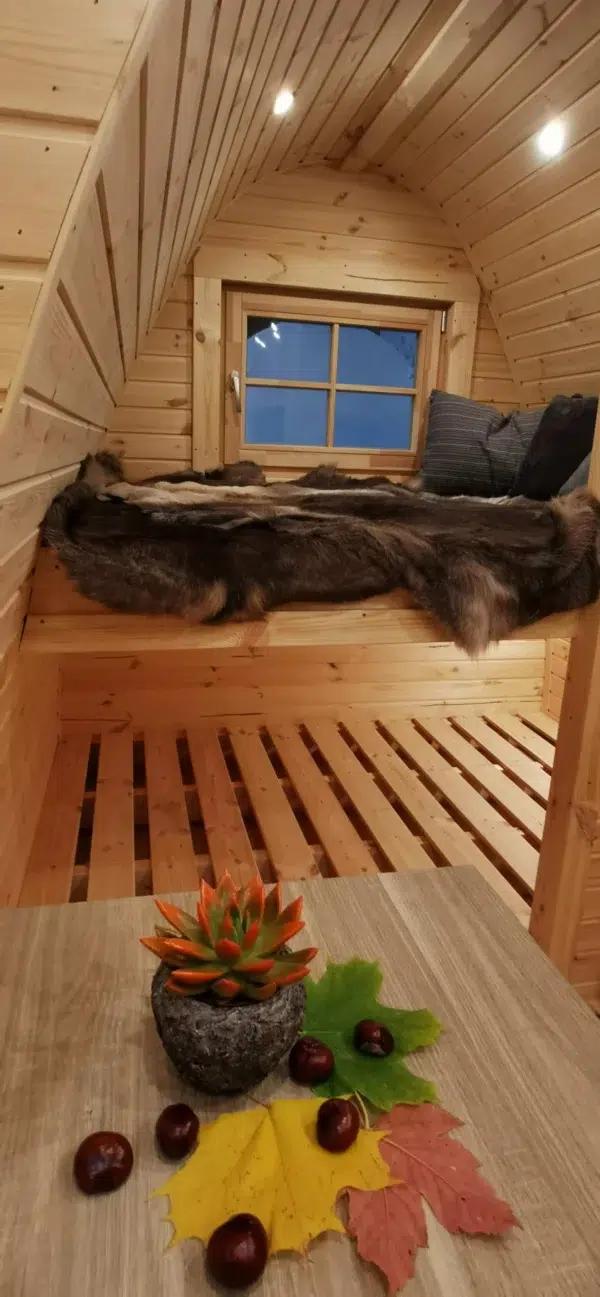 Wooden camping pod, raised sleeping area with lower slatted platform