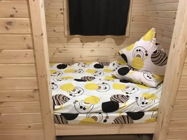 Wooden camping pod, separate sleeping area with patterned bedding