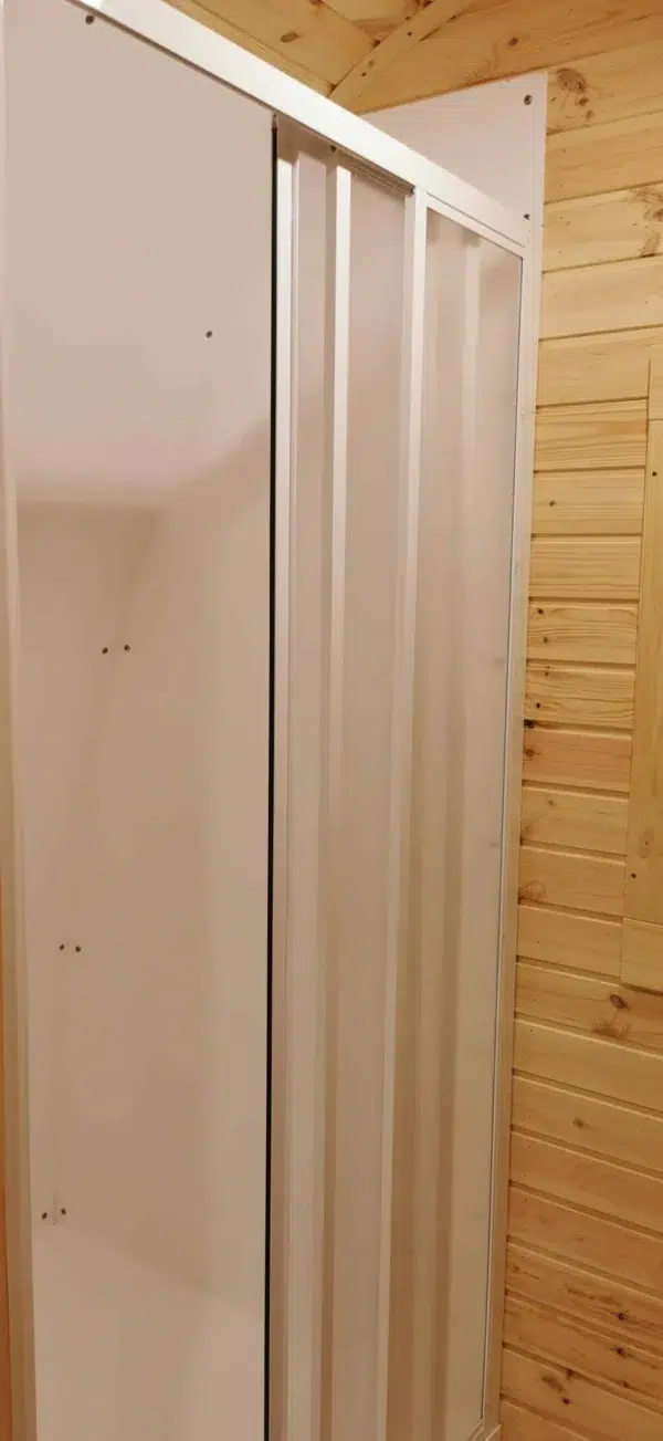 Wooden camping pod, shower enclosure beside wooden wall