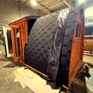 Wooden camping pod, side entrance and shingle roof in a workshop