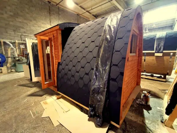 Wooden camping pod, side entrance and shingle roof in a workshop
