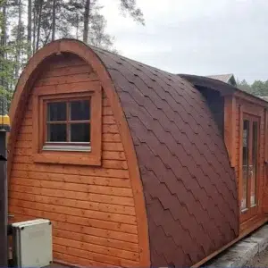 Wooden camping pod, side exterior with red shingle roof