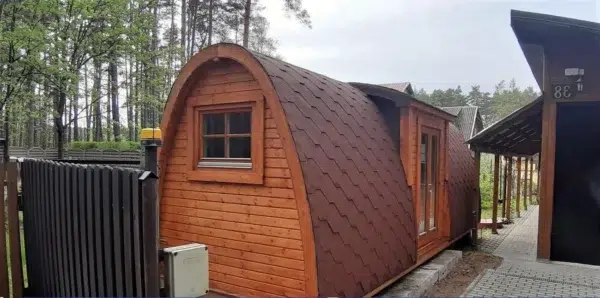 Wooden camping pod, side exterior with red shingle roof