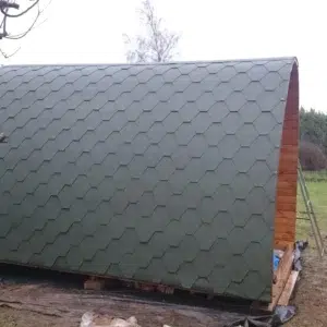 Wooden camping pod, side view of curved shingle roof