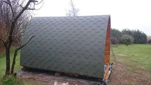 Wooden camping pod, side view of curved shingle roof
