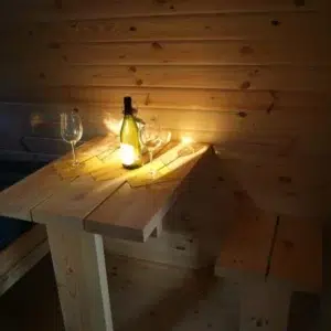 Wooden camping pod, table set with a bottle and glasses