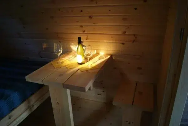Wooden camping pod, table set with a bottle and glasses