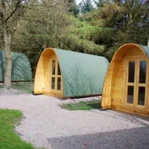 Wooden camping pod, three camping pods beside a gravel path