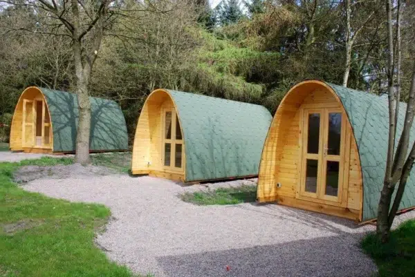 Wooden camping pod, three camping pods beside a gravel path