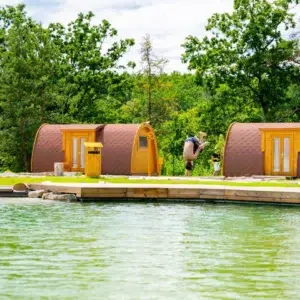 Wooden camping pod, two pods beside a swimming pond