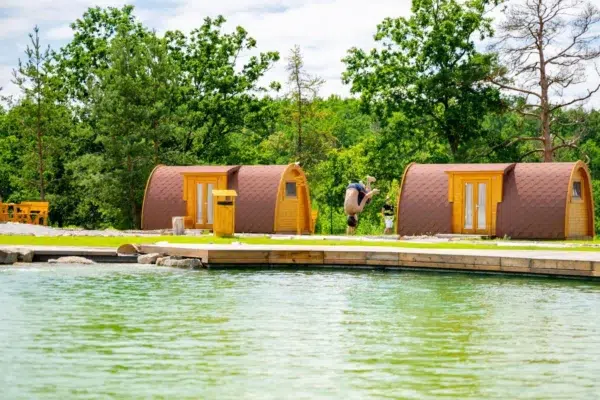 Wooden camping pod, two pods beside a swimming pond