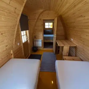 Wooden camping pod, view along central aisle between beds