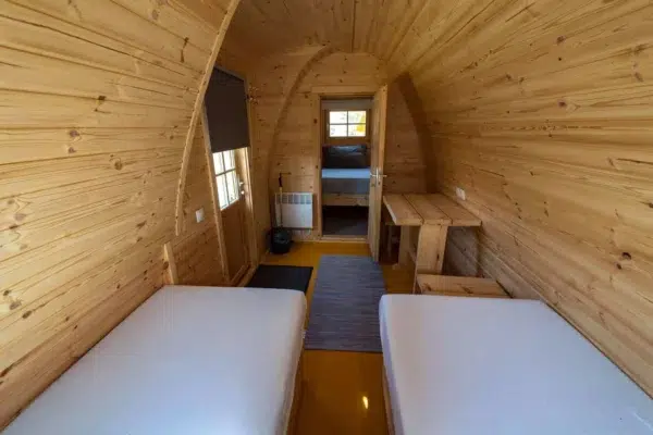 Wooden camping pod, view along central aisle between beds