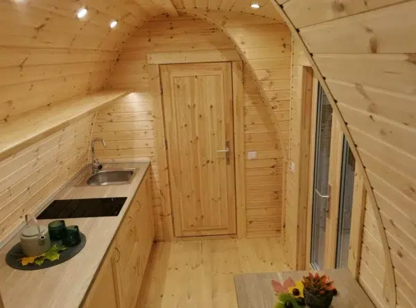 Wooden camping pod, view along kitchenette to internal door