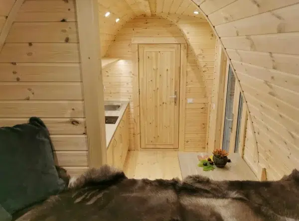 Wooden camping pod, view from raised bed toward kitchenette