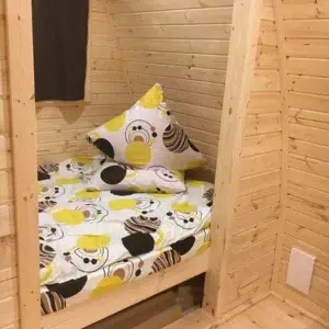 Wooden camping pod, view through doorway to a made-up bed