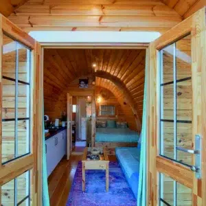 Wooden camping pod, view through open doors to furnished interior