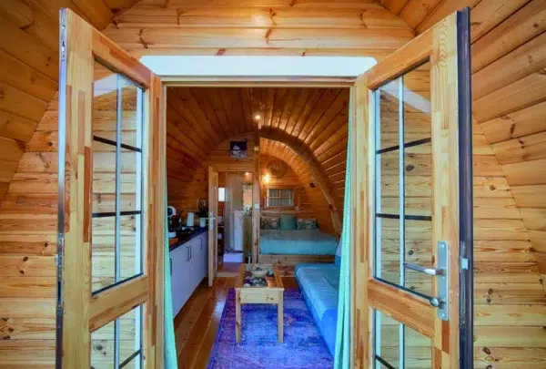 Wooden camping pod, view through open doors to furnished interior