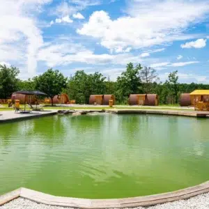 Wooden camping pod, wide view of camping pods around a pond