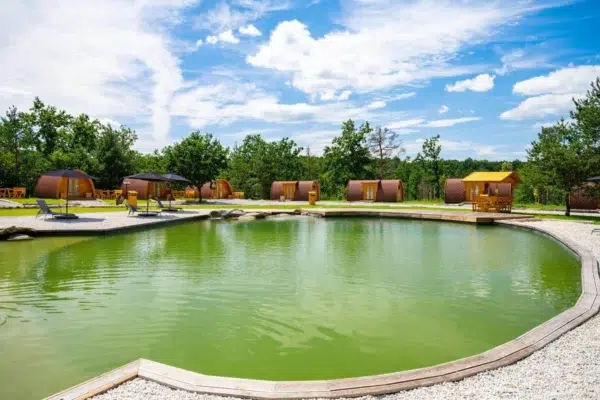 Wooden camping pod, wide view of camping pods around a pond