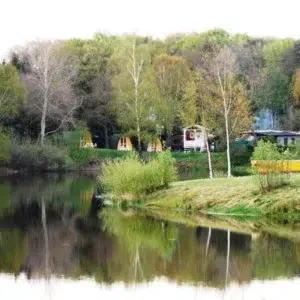 Wooden camping pod, wide view of a lakeside camping area