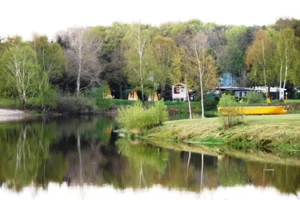 Wooden camping pod, wide view of a lakeside camping area