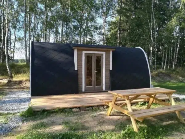 Wooden camping pod, woodland installation with entrance deck and picnic table