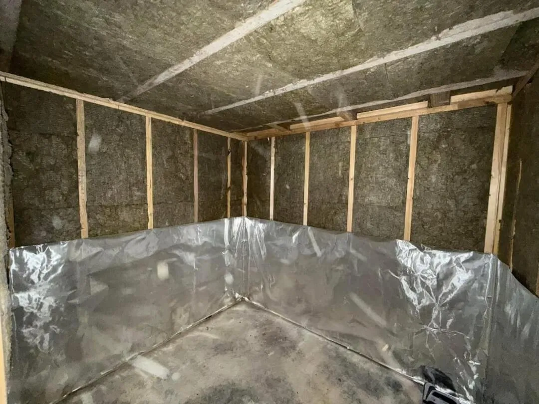 Sauna under construction with exposed wall insulation and foil partly installed