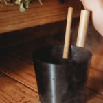 Rento Black sauna ladle with heat-treated bamboo handle in a sauna setting